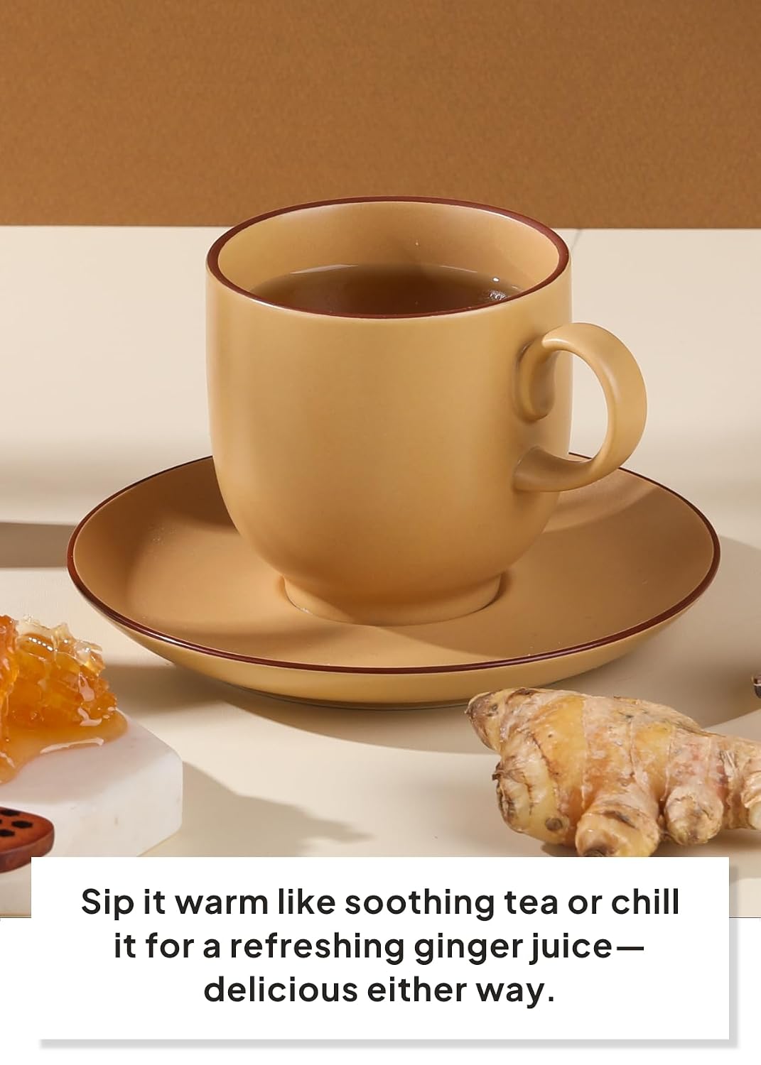 A beige ceramic tea cup with a matching saucer, filled with tea, set on a tabletop with ginger root and honey props. A text overlay at the bottom reads, 'Sip it warm like soothing tea or chill it for a refreshing ginger juice—delicious either way.