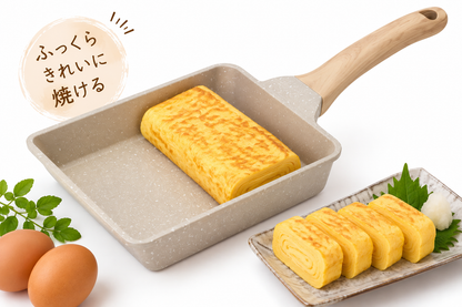 A square non-stick frying pan with a speckled beige exterior and a light wood handle, shown cooking an omelet. A plate with sliced omelets, green leaves, and two brown eggs are arranged around the pan on a white background, with Japanese text in the upper left.