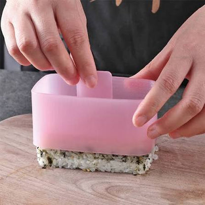 Person using a pink silicone sushi mold on a wooden surface